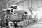 Lockheed mechanics take a break after completing mate operations on the fuselage of the first YC-130, the prototype of the C-130 Hercules, on 2 July 1953. More than thirteen months later, the fully assembled YC-130 would be flown for the first time from the company's facility in Burbank, California, to the Air Force Flight Test Center at Edwards AFB. The large opening in the fuselage is for a side-opening cargo door that was later deleted on production C-130s.